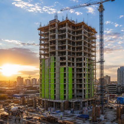 High-rise tower under construction with tower cranes at sunset