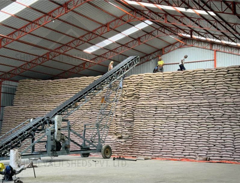 Close-up of the sack wall inside the storage shed with inclined conveyor and workers stacking bags on top