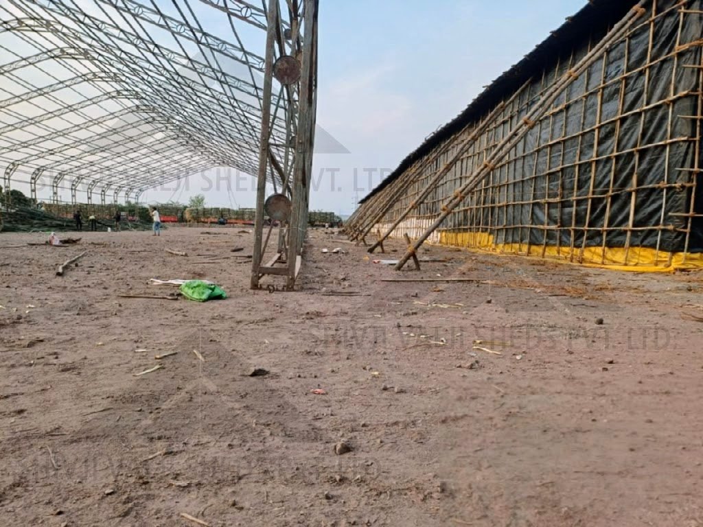 Dusk shot of the arched hangar frame with workers climbing the trusses